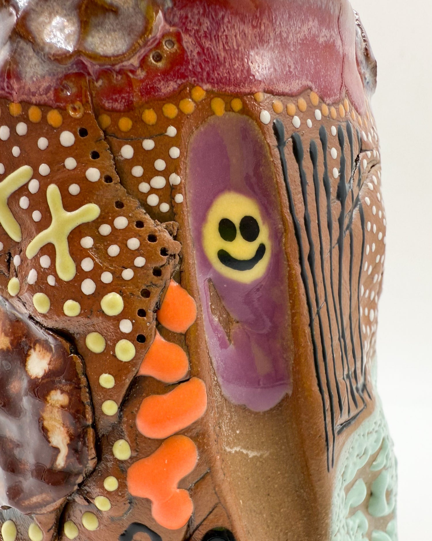 zoomed in photo of a yellow smiley face made from yellow glaze on a travel mug