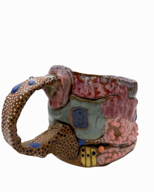 Pictured is a handmade ceramic mug that is full of gloops and globs allowing the mug holder to have a tactile experience while enjoying their peferred drink.